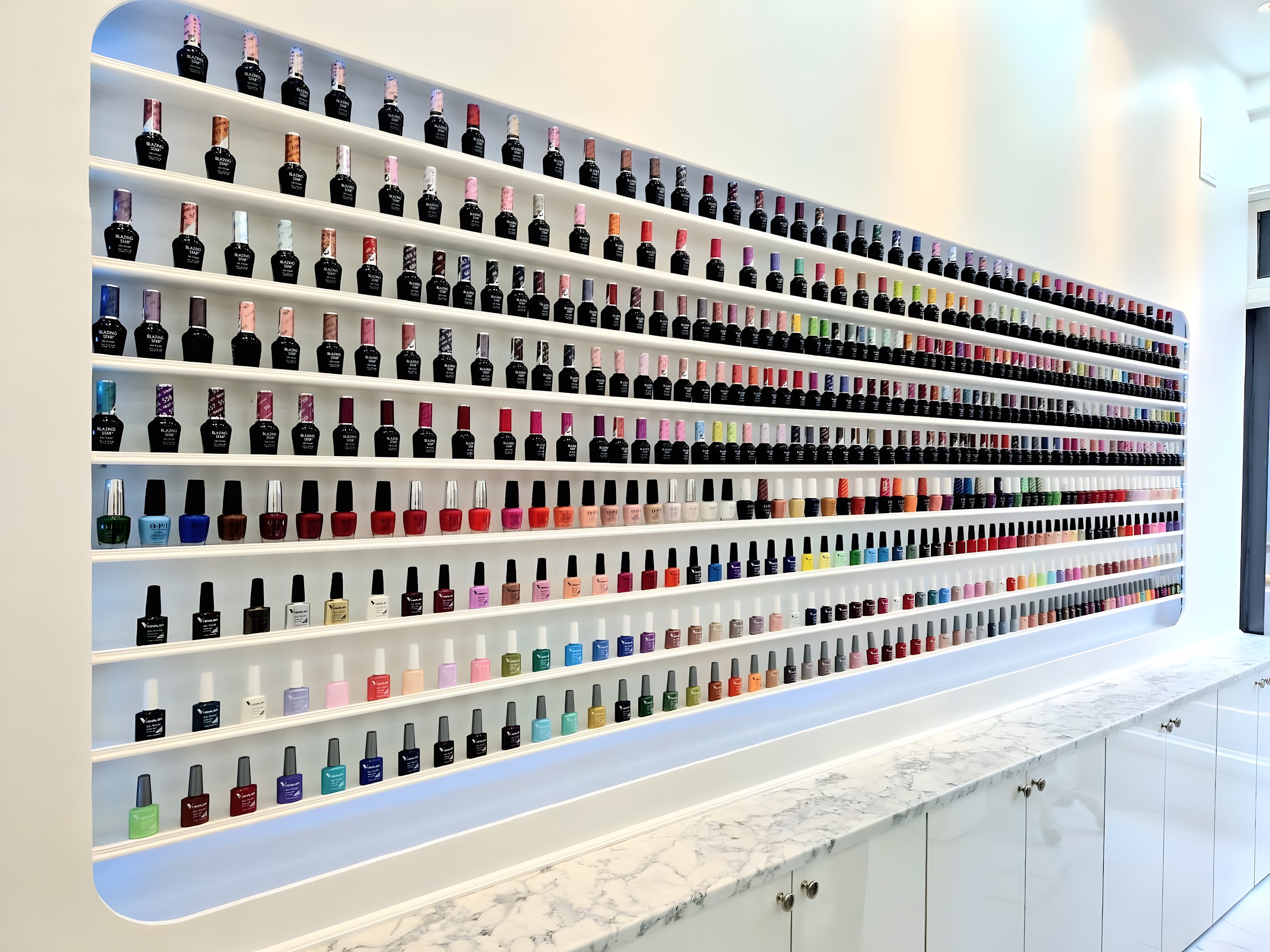 A wall of hundreds of nail-polish shades and a marble counter inside Hailey Nail Spa