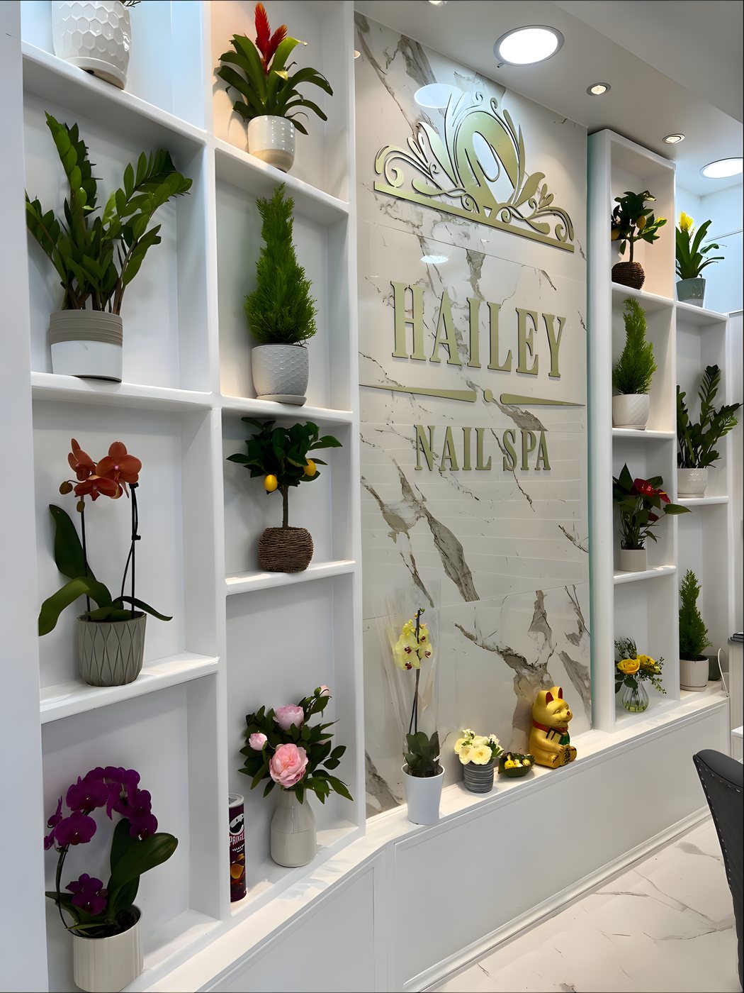 The marble feature wall and gold lettering inside Hailey Nail Spa, with trailing plants